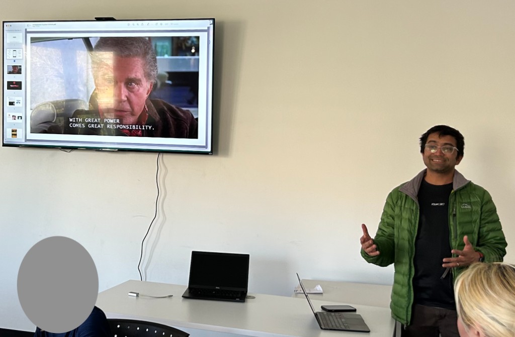 A member giving a talk in front of a slide reading "with great power comes great responsibility."